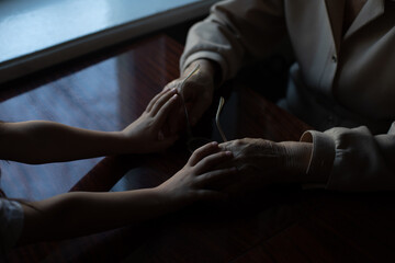 Young granddaughter taking care of grandmother with tender and care. Wrinkled hands of very old woman and young hands of teen woman close up, the change of family generation. Healthcare and wellness.