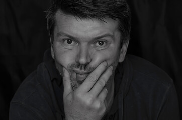 Body language  concept. Black and white portrait of an adult man supporting his head with fist.