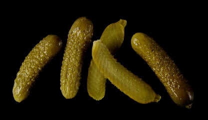 Pickled gherkin pile, pickles isolated on black background, top view