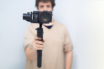 unfocused man gripping a gimbal with a mounted mirrorless camera.blog concept