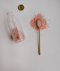 pink salt on the white table in wooden spoon