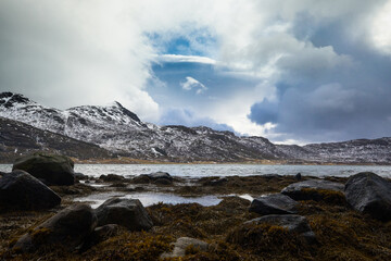 Beautiful landscape. Lofoten Islands. Stones on the background of snow-capped mountains and clouds.