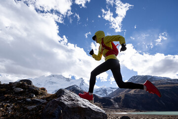 Woman trail runner cross country running in high altitude winter mountains