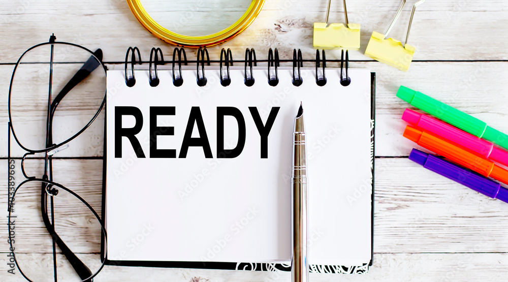 Poster ready written in a notebook on white background with office tools