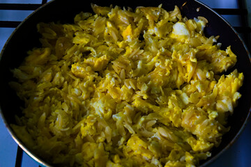 Scrambled eggs with greek noodles called Kritharaki fried in a pan