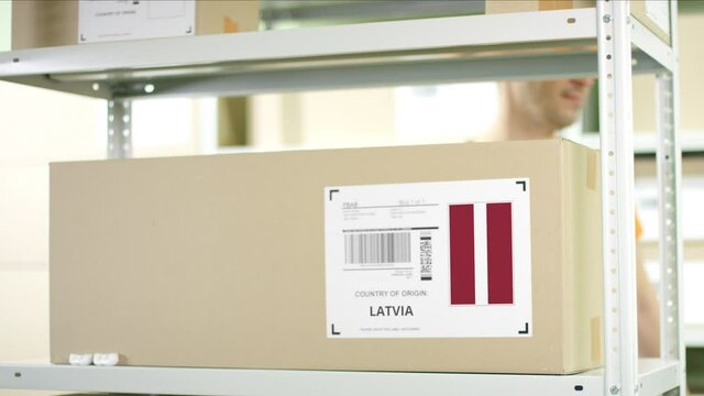 Worker puts a carton with goods from Latvia on the shelf