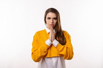 Attractive brunette girl prays for wellness of family, keeps palms pressed together in praying gesture, saying namaste