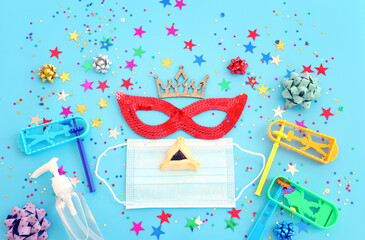 Purim celebration concept (jewish carnival holiday) over blue background. Top view, Flat lay. Coronavirus prevention concept, medical mask and sanitizer gel
