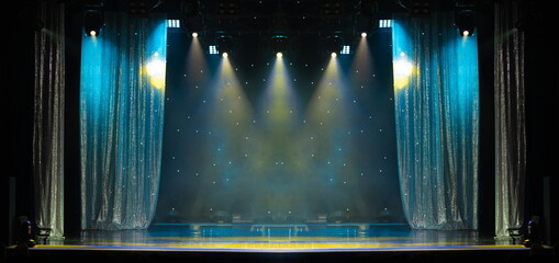 An empty stage of the scene concert hall, lit by spotlights and smoke 