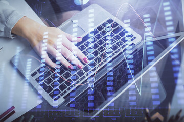 Double exposure of businesswoman hands typing on computer and financial graph hologram drawing. Stock market analysis concept.