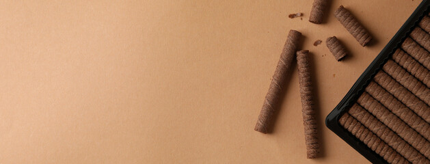Plastic box with chocolate wafer rolls on brown background