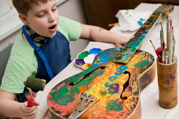 kid have fun painting guitar. color gouache art therapy lesion.