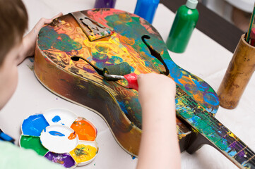 kid have fun painting guitar. color gouache art therapy lesion.