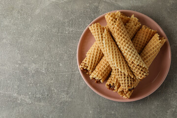 Plate with wafer rolls with condensed milk on gray background