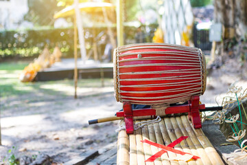 Traditional Thai style wooden drum on wooden table over blurred garden background
