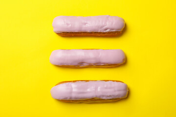 Delicious eclairs with custard on yellow background
