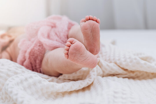 Small feet of newborn baby lieing on the bed. Soft focus.