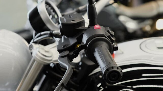 Close-up of motorcycle left rubber grip, brake lever, lighting control buttons, hazard warning button. Cinematic shot.