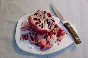Peeled pomegranate fruit on a plate and knife