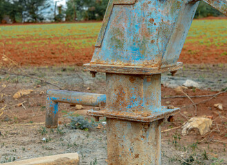 Fototapeta na wymiar Old Water Pump near grass field used for Farming 