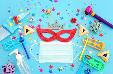 Purim celebration concept (jewish carnival holiday) over blue background. Top view, Flat lay. Coronavirus prevention concept, medical mask and sanitizer gel