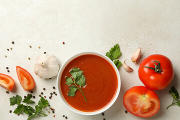 Bowl with tomato soup and ingredients on light background