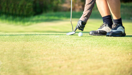 Obraz premium Close up Hand asian woman putting golf ball on tee with club in golf course on sunny day for healthy sport. Lifestyle Concept.