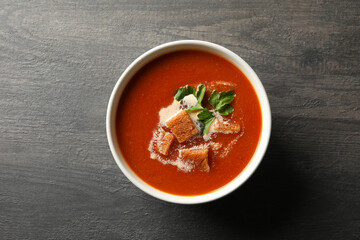 Bowl of tasty tomato soup on dark wooden background