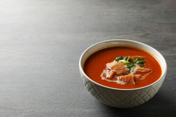 Bowl of tasty tomato soup on dark wooden background