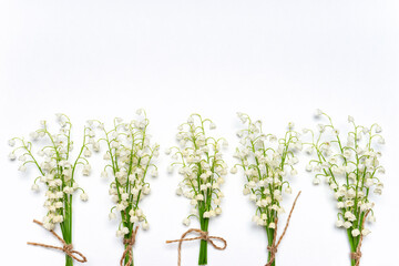 Bouquets of fresh lilies of the valley flowers on white background. Creative composition, mock up for greeting card for holiday event. Flat lay, top view, copy space