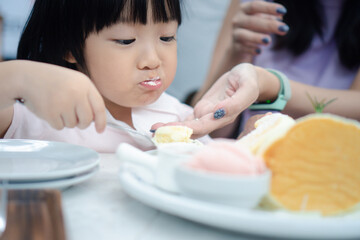 Obraz na płótnie Canvas Asain cute girl eat dessert pancake with spoon. Concept for kid and family lifestyle.