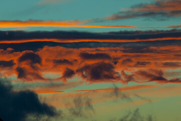 sky with unusual amazing clouds of rich and soft colors at sunset