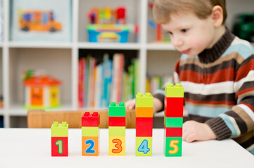Learning to count. 2 year old boy stacking Duplo blocks. children, infancy and education concept. formation and development of the child. Montessori and early development