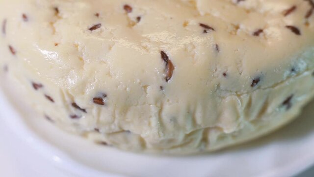 Fresh cheese with cumin. Cumin sprinkled on cheese. The tray rotates. Selective focus