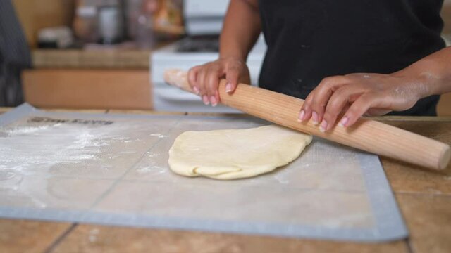 Black woman using rolling pin on dough in home kitchen, Slow Motion Close Up