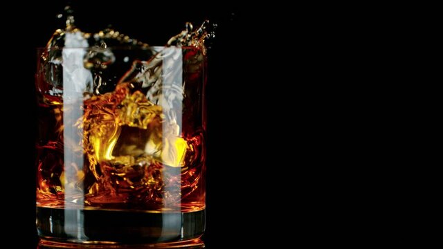 Ice Dropped into Glass of Whisky in Super Slow Motion. Shot with High Speed Cinema Camera, 1000fps.