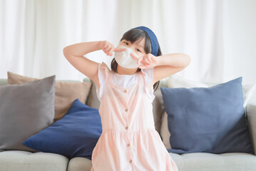 Asian little cute girl wearing hygienic face mask for prevent coronavirus or Covid-19 outbreak keep social distancing and stay at home.