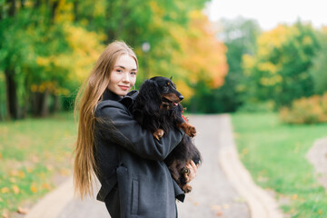 Happy woman holding her little dog in arms