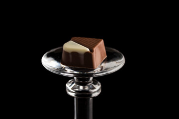 Closeup shot of chocolate placed on a small glass bowl on a black background