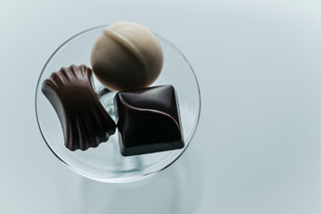 Overhead shot of chocolate pieces placed on a small glass bowl on a white background