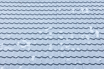 Close-up tiled roof texture covered with a thin layer of snow on a frosty day. Winter pattern