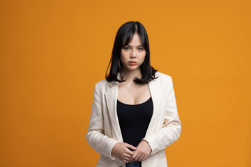 Obraz premium Attractive Beautiful asian woman standing and posing. Sexy female in suit on isolated yellow background.