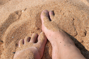 Sand covering female feet on a beach