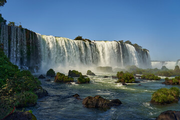 Fototapeta premium Iguazu Falls or Iguacu Falls, on the border of Argentina and Brazil, are the largest waterfall in the world. Very high waterfall with white water in beautiful rain forest landscape in the jungle