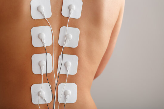 Muscle stimulator with electrodes, bacBack and shoulder massage with a muscle stimulator with attached electrodes along the spine.