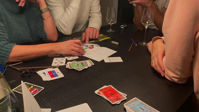 Family playing mystery game named Exit indoors on black table. Static close up.
