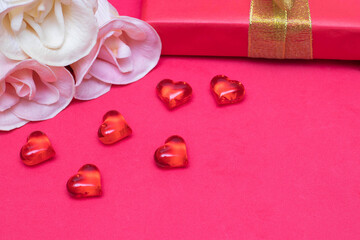 Congratulations on Valentine's Day: roses, a gift box and hearts on a red background, copy space. The photo
