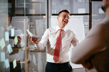 Business people in conference room use sticky notes on glass wall. Colleagues working on new project.