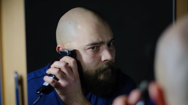 A man shaves off his beard with a shaving machine, close-up. The concept of changing the image 