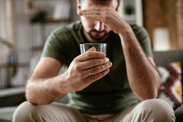 Depression man drinking alcohol at home. Lonely man is addicted of alcohol.